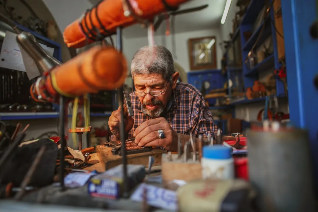 An elderly man working with his hands on a traditional craft in his workshop