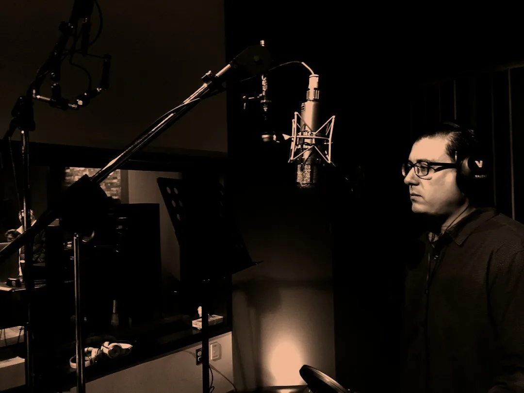 A man standing at a microphone in a recording room