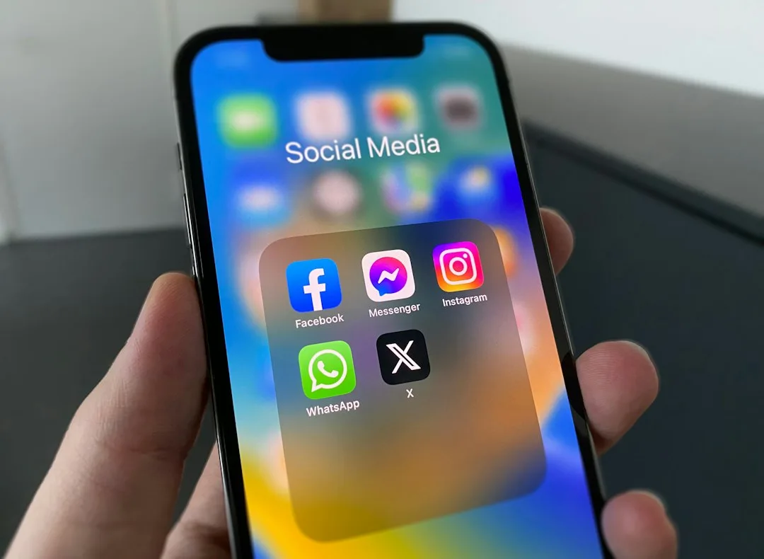 A hand holding a phone showing social apps