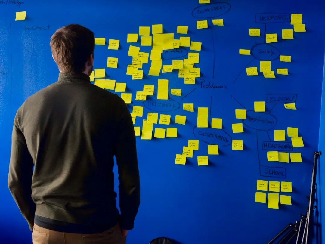 A person standing at a wall of yellow sticky notes