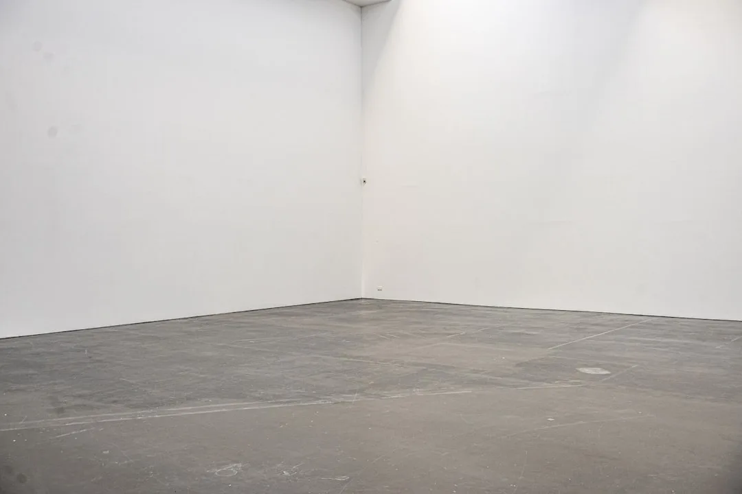 An empty room with white walls and a bare floor
