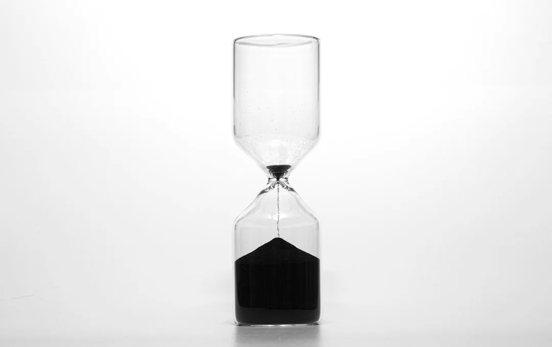 A glass hourglass on a dark surface