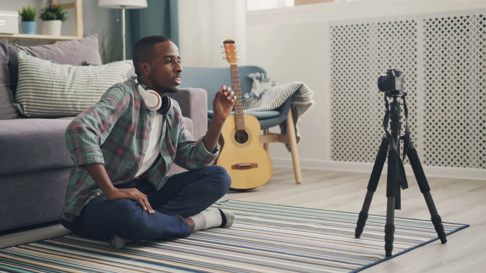 A young man sitting in front of a camera at home, recording himself talking