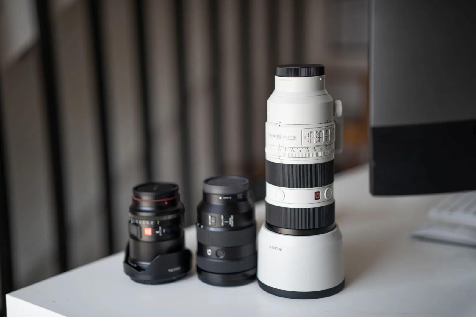 Camera lenses laid out on a table, their focal length numbers visible on the barrels