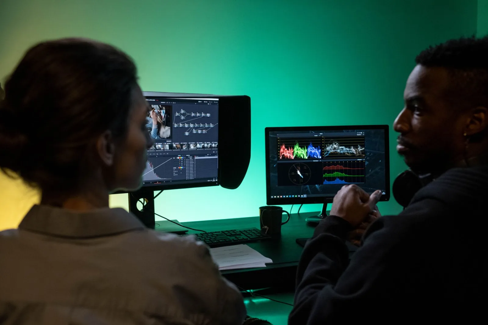 Two people reviewing a cut on dual monitors and discussing the edit