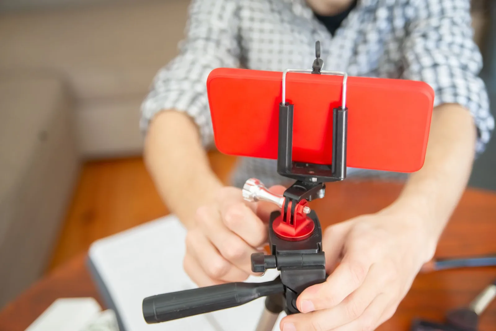 A hand adjusting a phone mounted on a tripod at the filming position