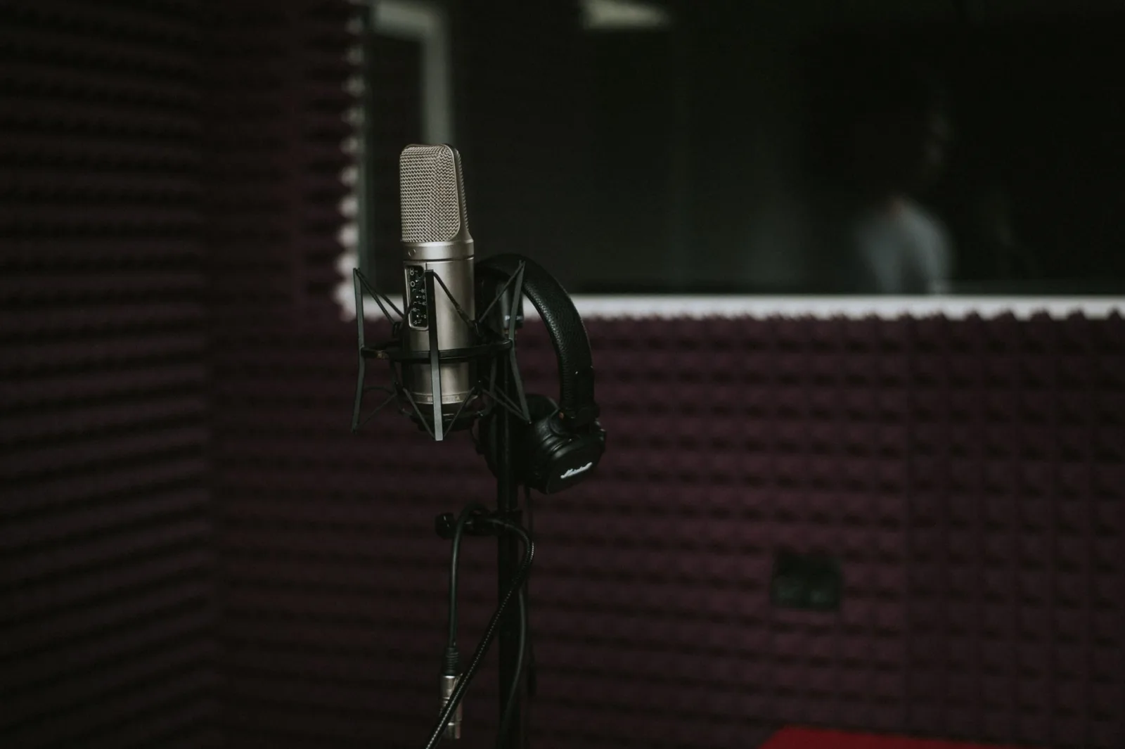 A microphone and headphones inside a soundproofed recording booth