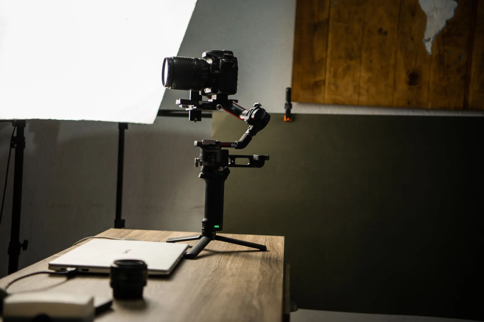 A camera mounted on a gimbal beside filming gear in a workroom