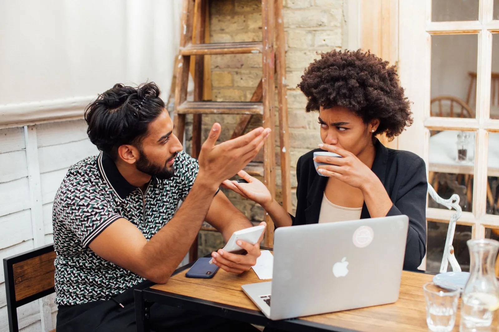 Two people working together at a laptop discussing a task