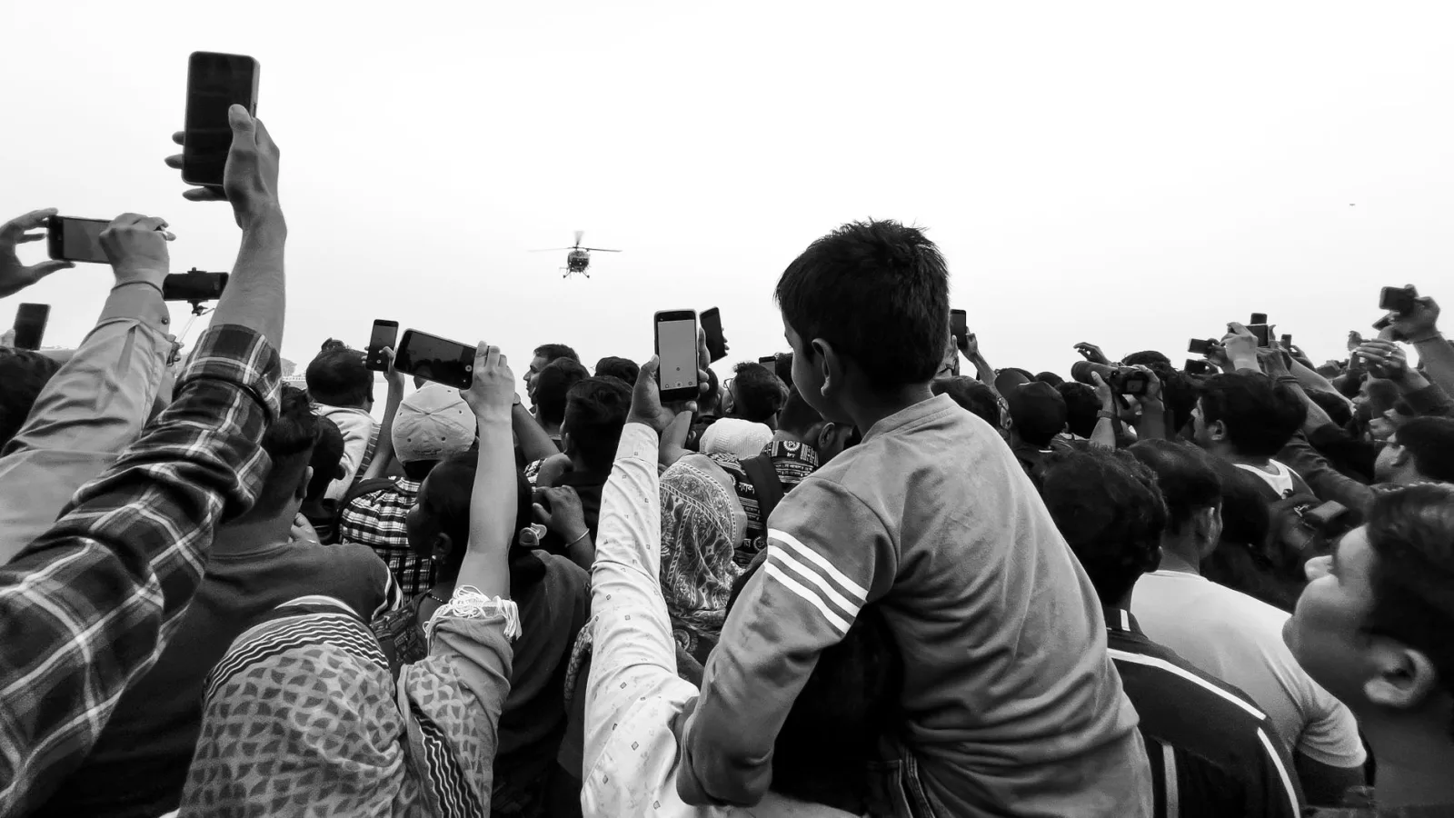 A crowd of people raising their phones to film the same scene