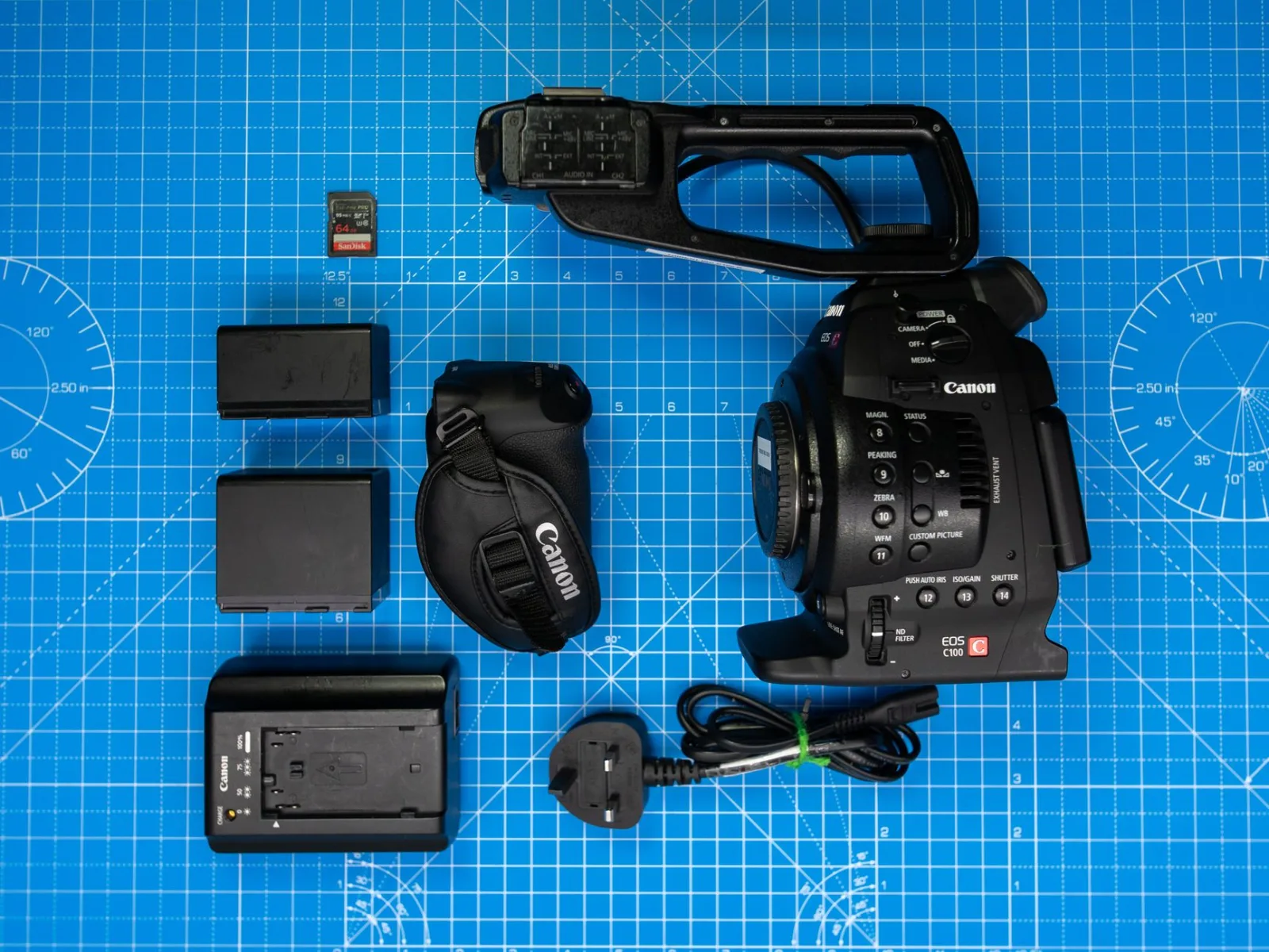 Camera batteries, a memory card and a lens laid out on a surface