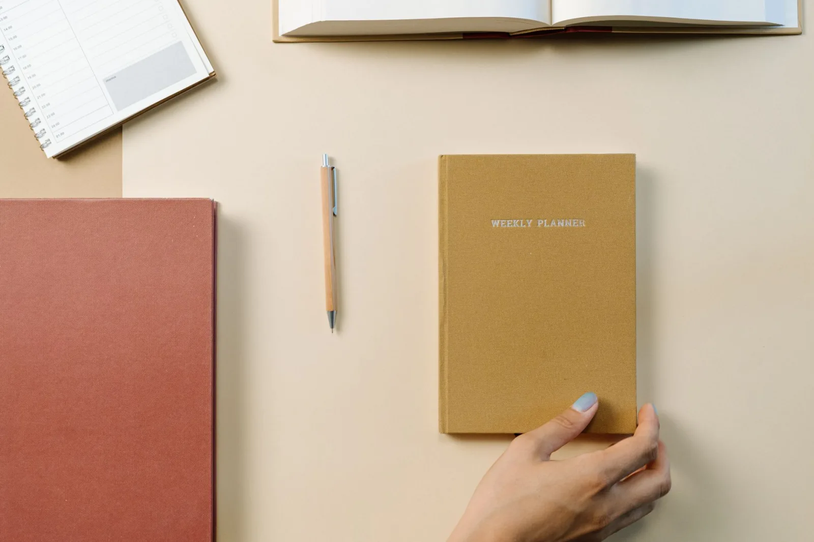 A weekly planner, a notebook and a pen on a desk