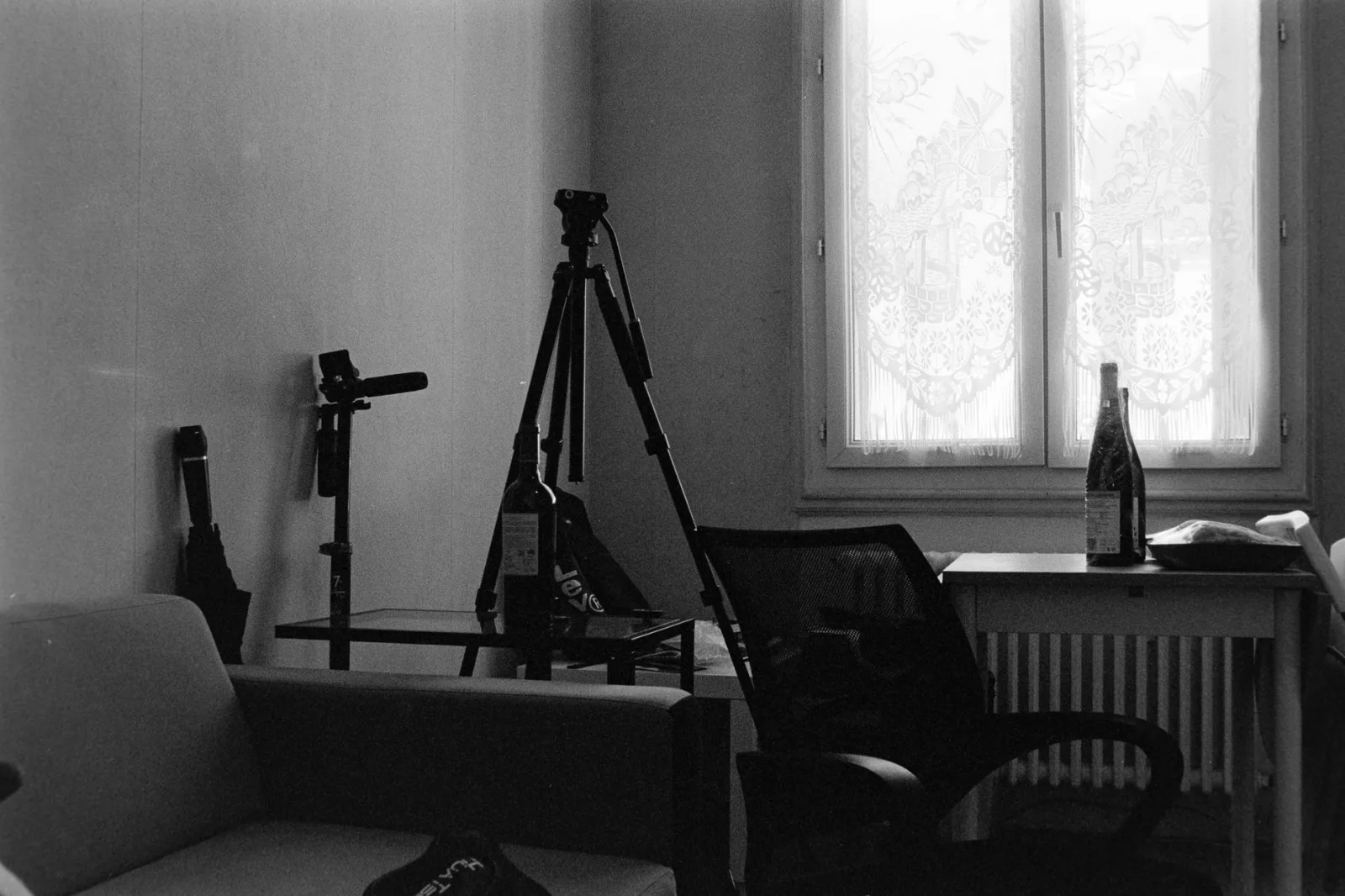 A camera on a tripod aimed at a seat beside a window